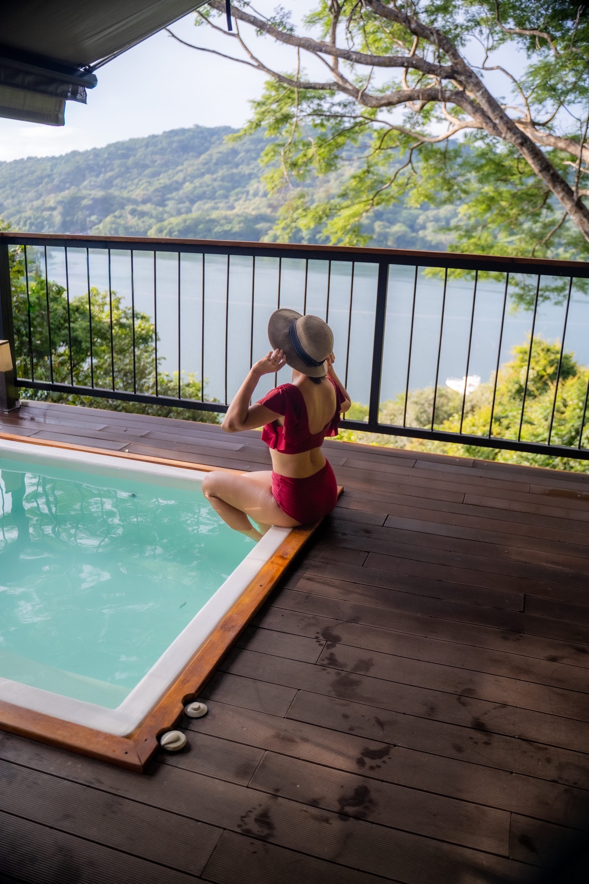 Huésped con sombrero junto a una piscina de madera frente a una bahía, en una colaboración de Cool Producciones