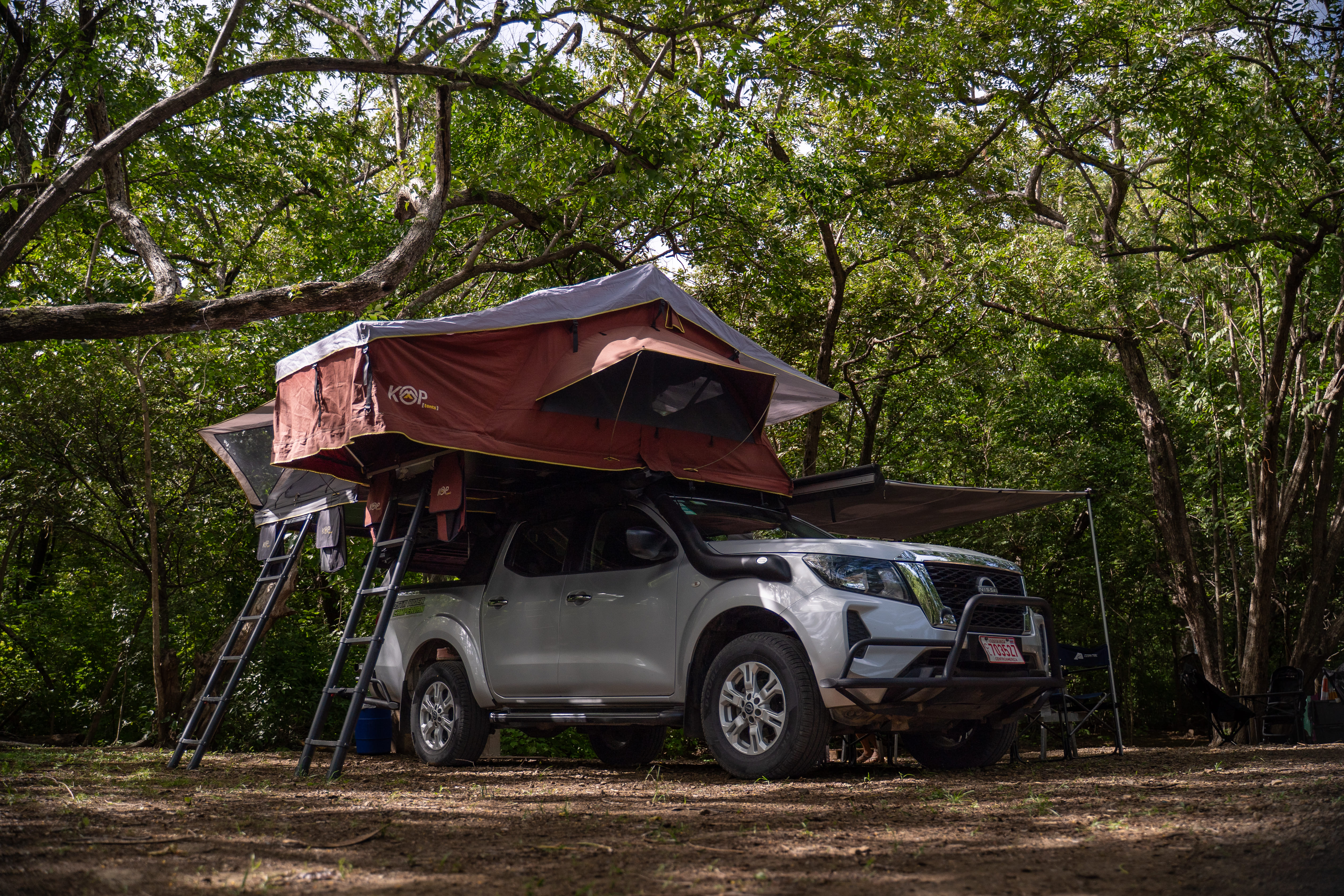 Campervan con tienda de techo montada en el área de camping del refugio
